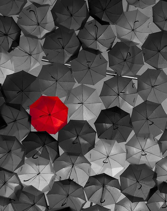 Red umbrella in a sea of black umbrellas